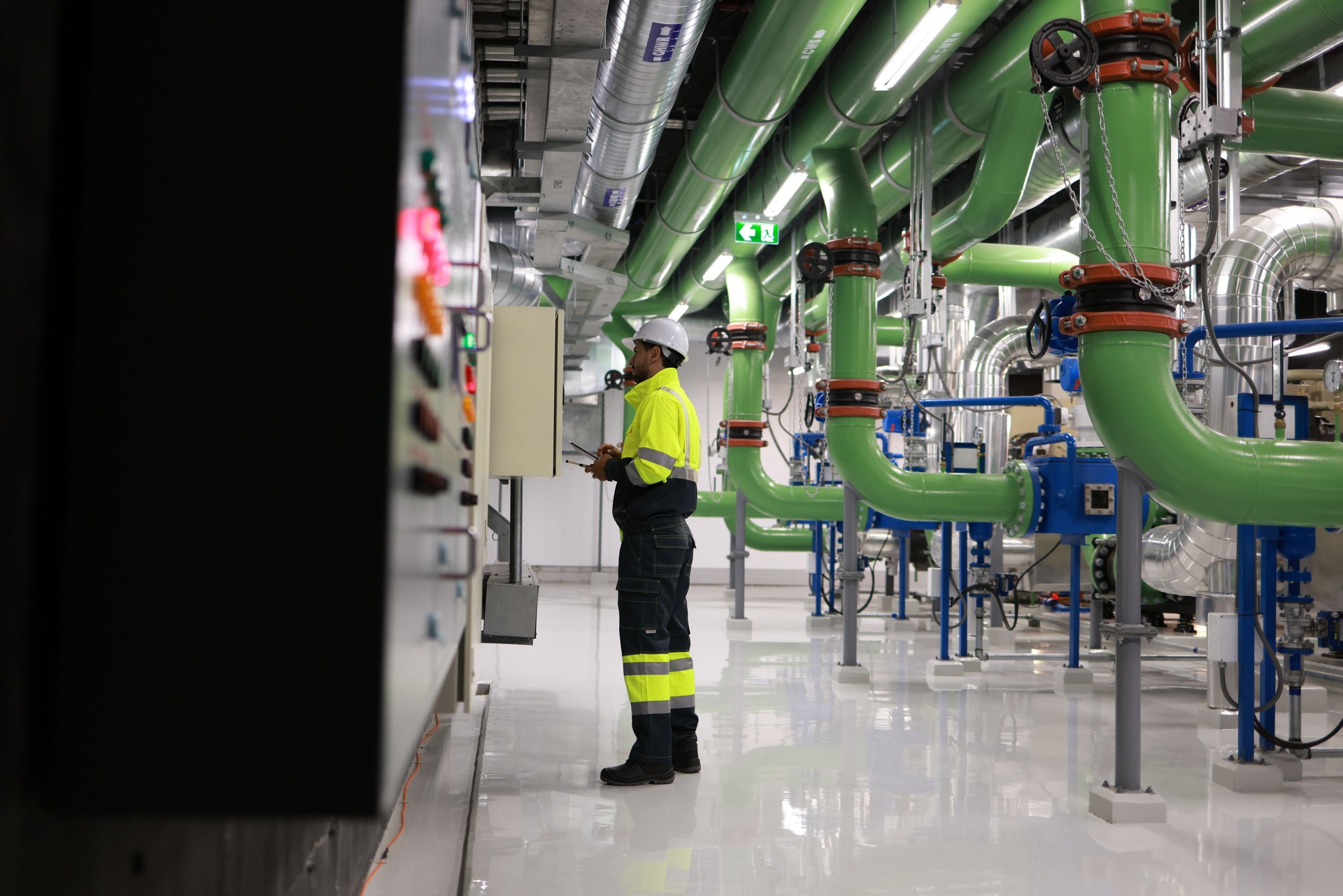Specialist HVAC Industrial engineer with green safety jacket and PPE check piping and HVAC control system, maintenance service